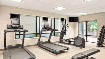 A gym with treadmills, a stationary bike, and a bench.