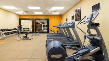 Un gimnasio con cintas de correr, mancuernas y equipo de ejercicio.
