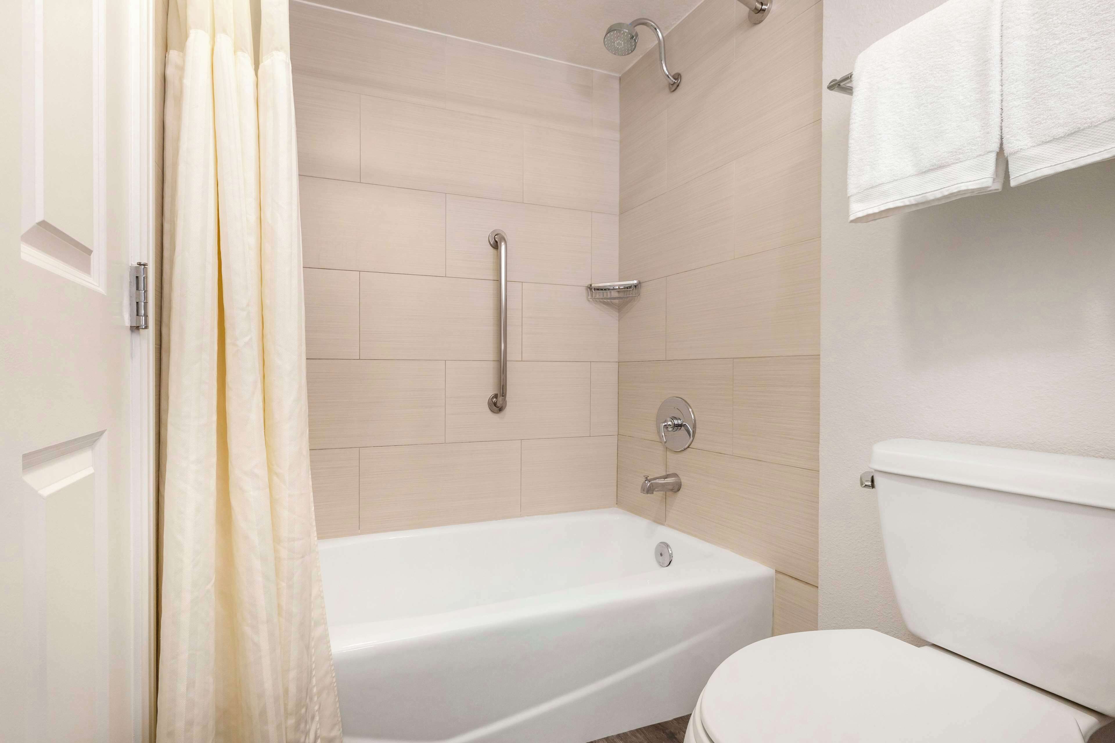 A bathroom with a bathtub, toilet, shower, and a towel rack.