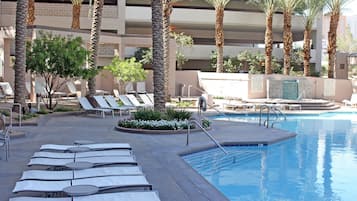 A pool area with lounge chairs and palm trees.