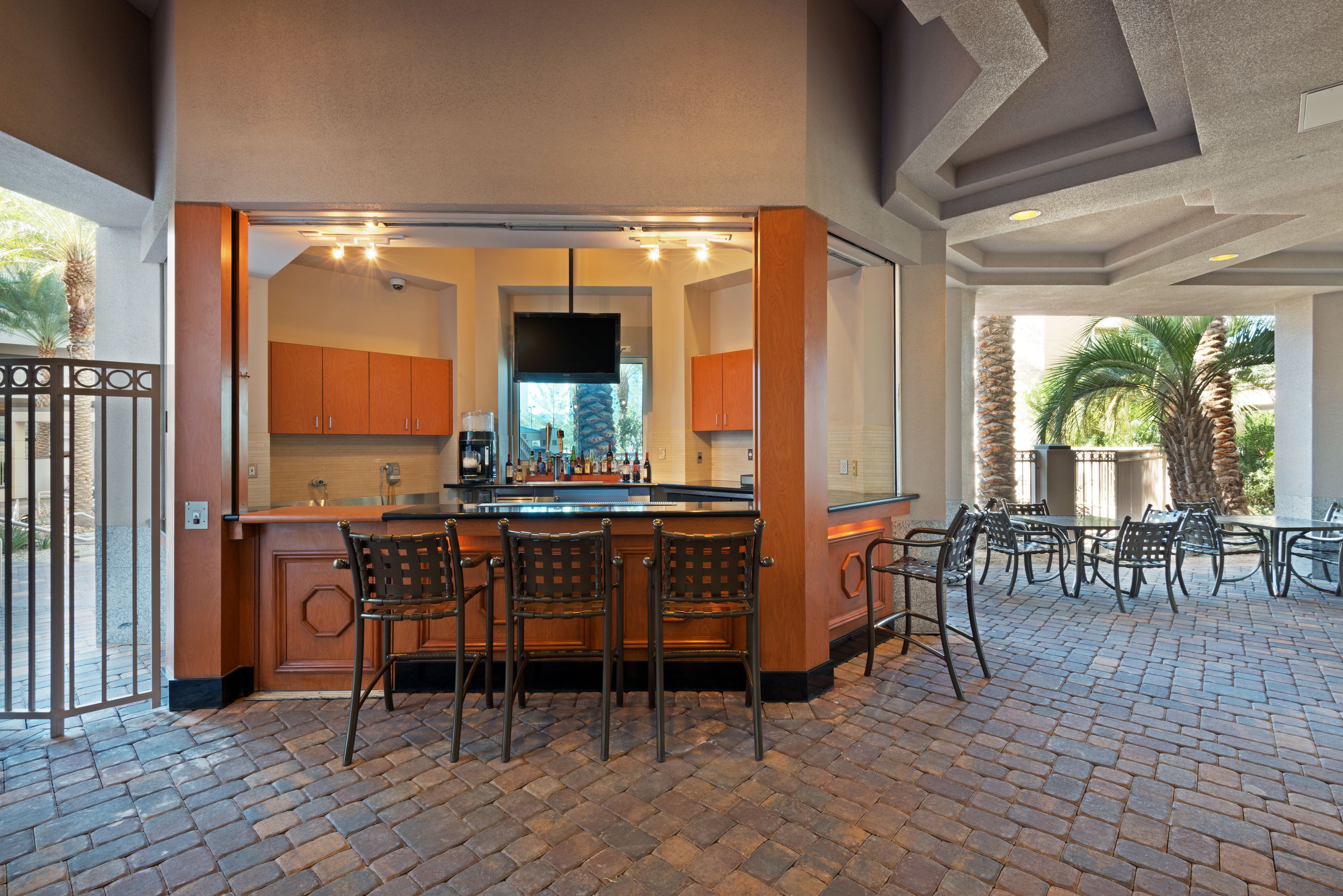 A bar area with a brick floor, wooden bar counter, and metal chairs.