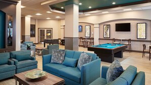 A spacious lounge area with blue sofas, a pool table, and a billiards table.