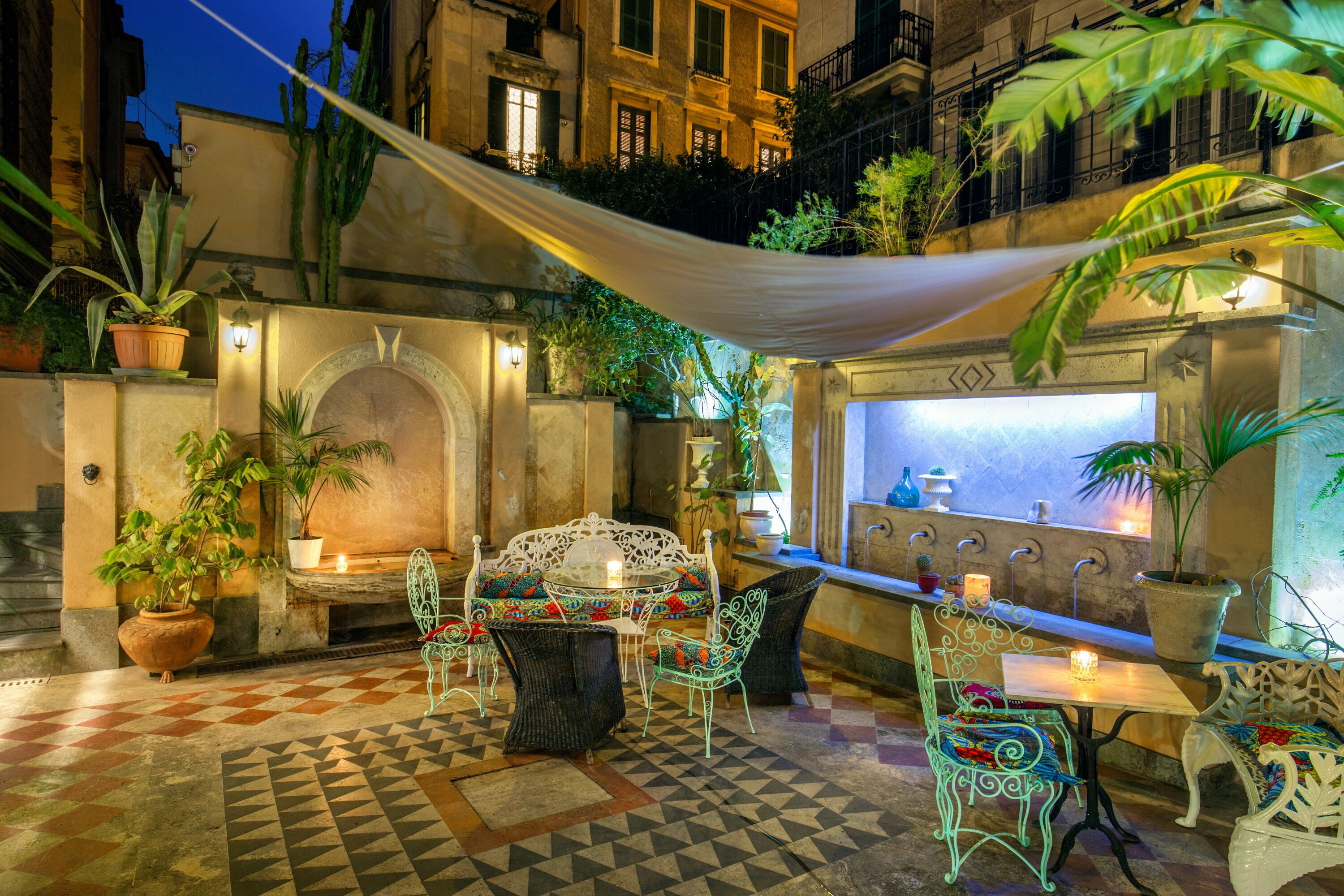 An outdoor patio with a checkered floor, metal chairs, a table, and potted plants.