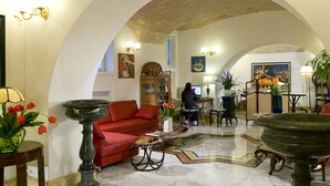 Eine geräumige Lobby mit einem roten Sofa, einem Schachbrett und einer großen Fontäne.
