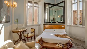 Ein Hotelzimmer mit einem Bett, einem Sessel, einem kleinen Tisch und einem großen Spiegel.