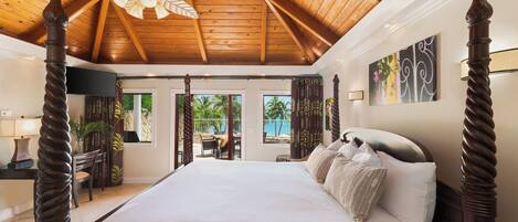 A spacious bedroom with a large bed, wooden ceiling beams, a ceiling fan, and a view of the outdoors.