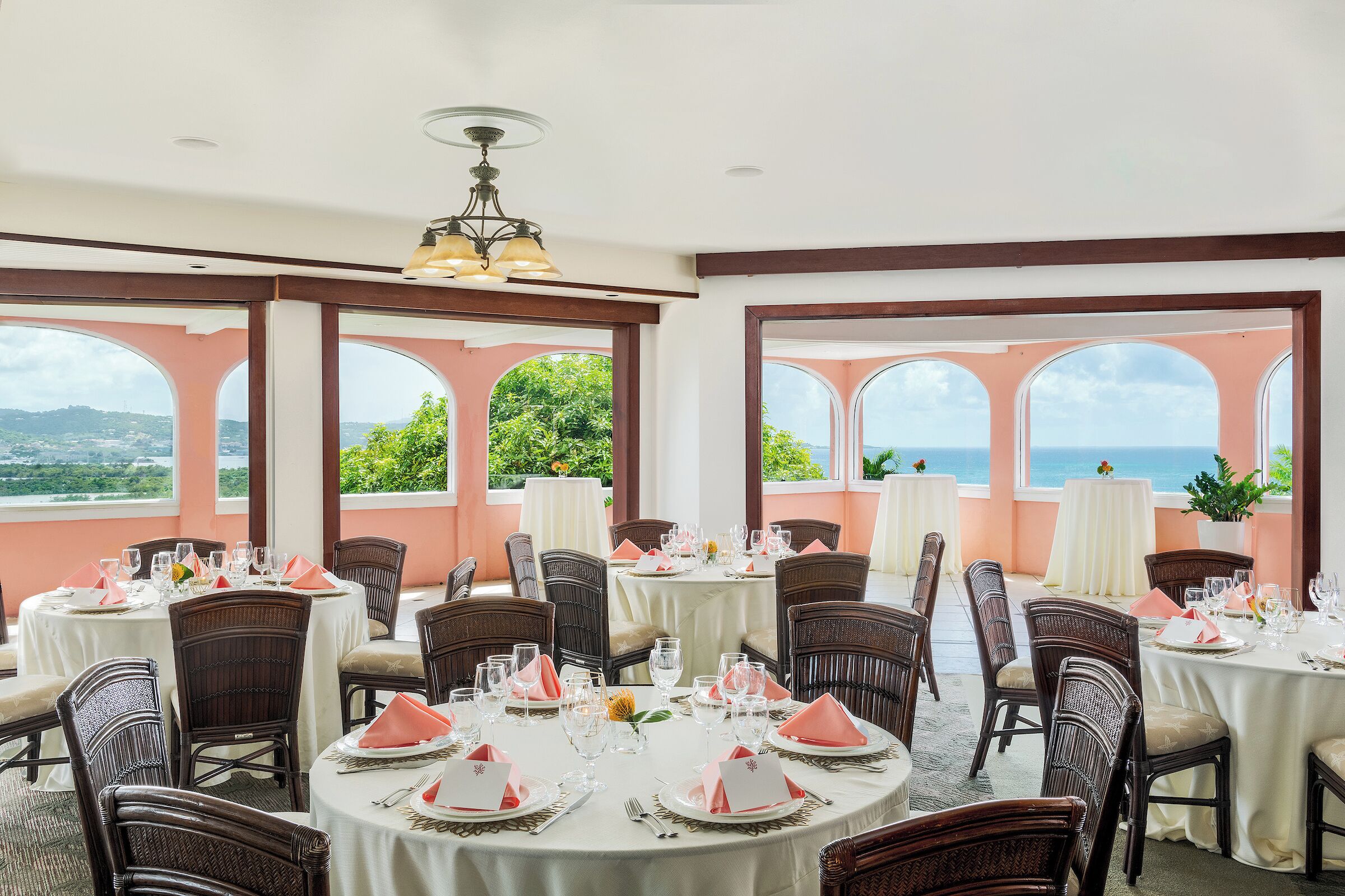 A dining area with round tables, chairs, and a view of the ocean.