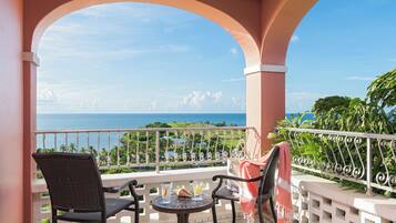 Ein Balkon mit zwei Stühlen, einem kleinen Tisch und Blick aufs Meer.