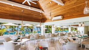Un vaste espace extérieur aménagé pour les repas, avec des meubles en osier et une vue sur la piscine.