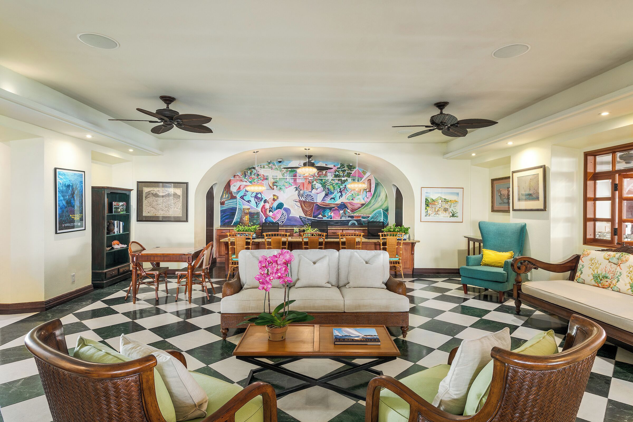 A lobby with a checkered floor, a sofa, chairs, a coffee table, and a mural on the wall.