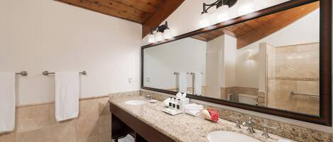 Un bagno moderno con soffitto in legno, due lavabi, uno specchio grande e un porta asciugamani.