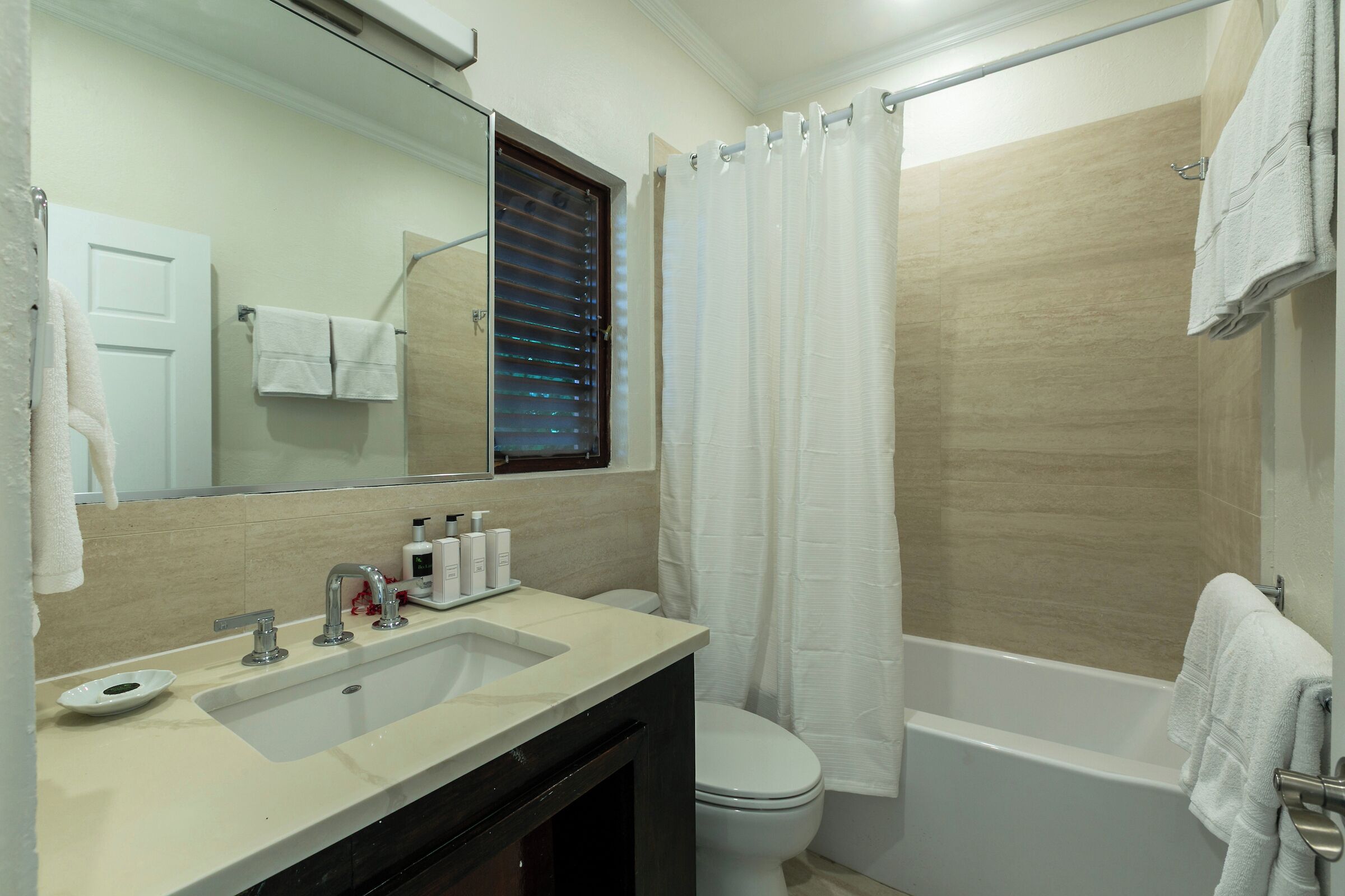 A bathroom with a sink, mirror, toilet, and bathtub.