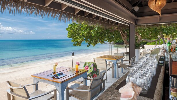 Un restaurant situé en bord de mer, avec une terrasse, une vue sur l’océan et un toit de chaume.