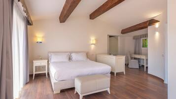 A bedroom with a bed, bedside tables, a desk, and a chair.