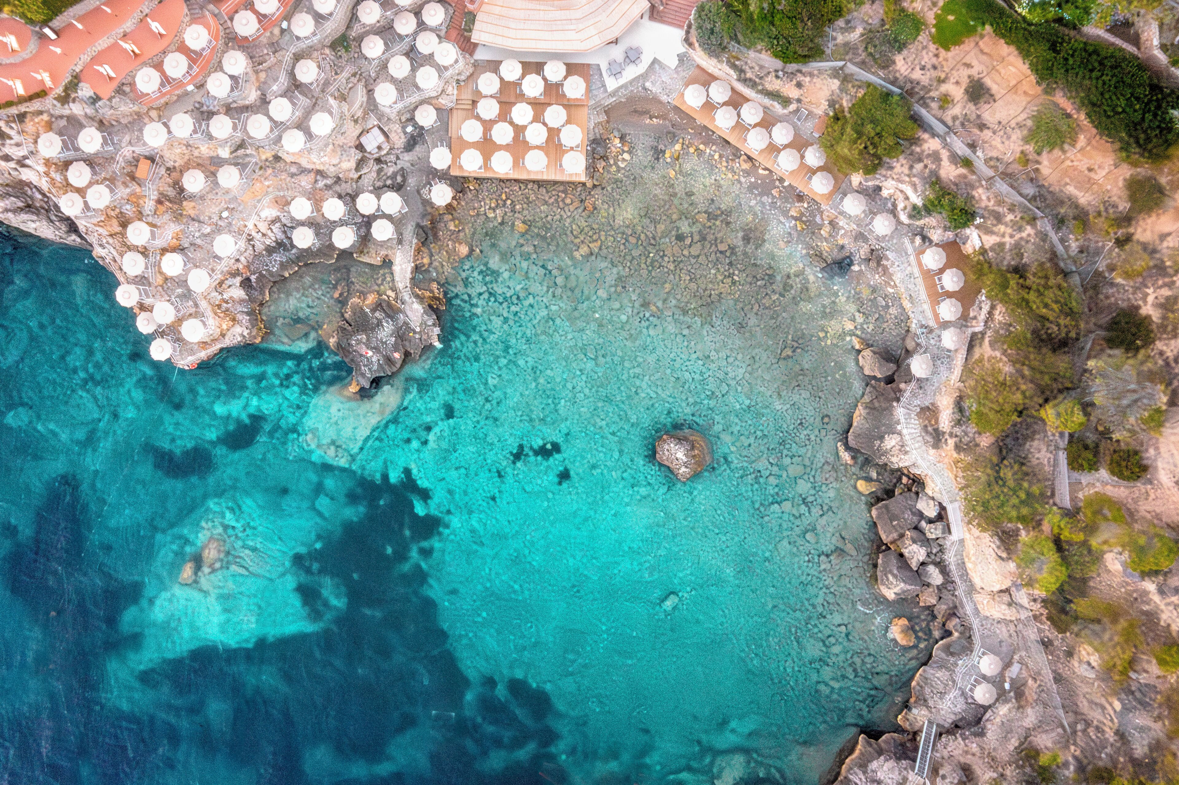 Luftaufnahme eines Küstenresorts mit Außenbereich und felsiger Küstenlinie.