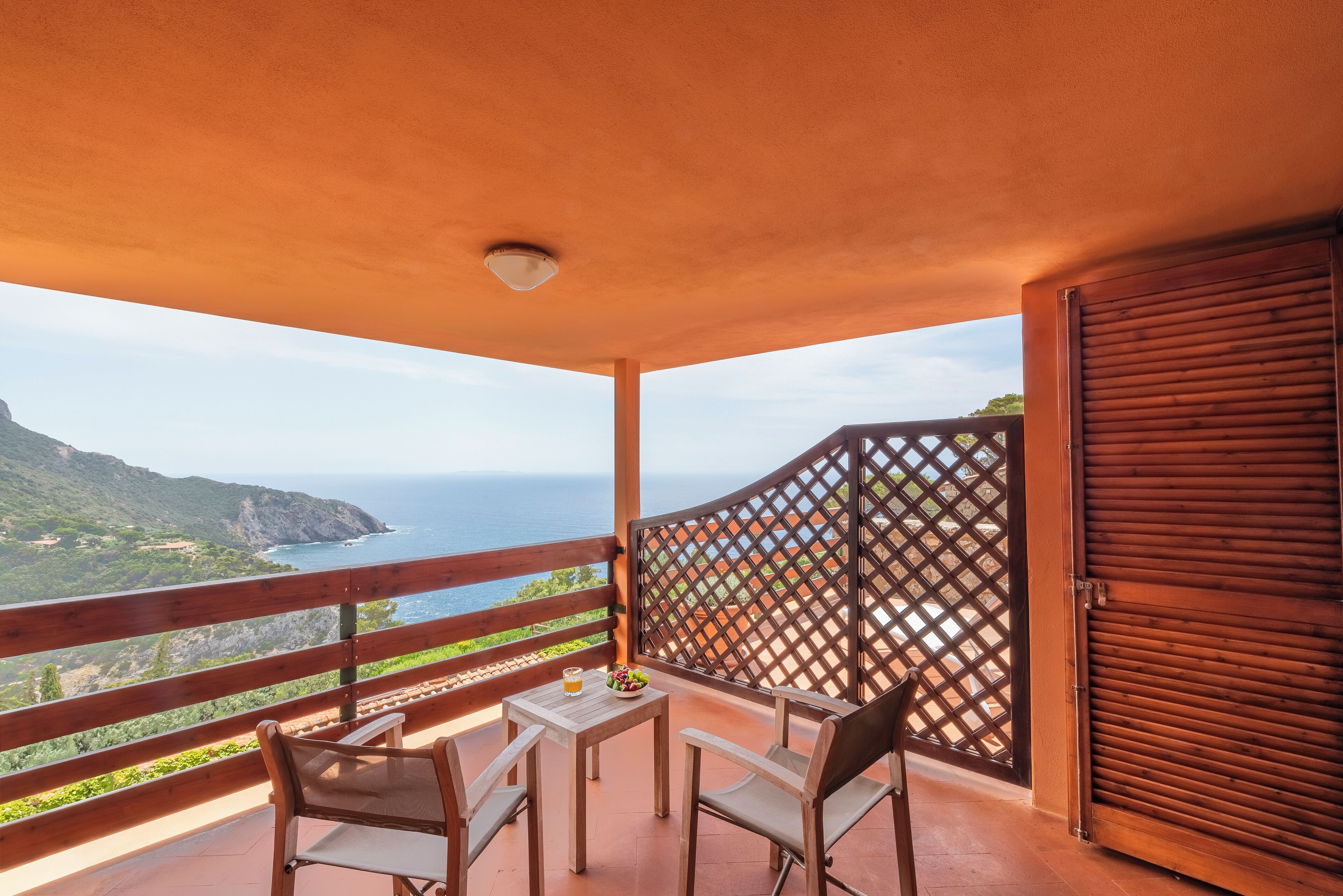 En balkon med et bord og stole, havudsigt og en træpergola.