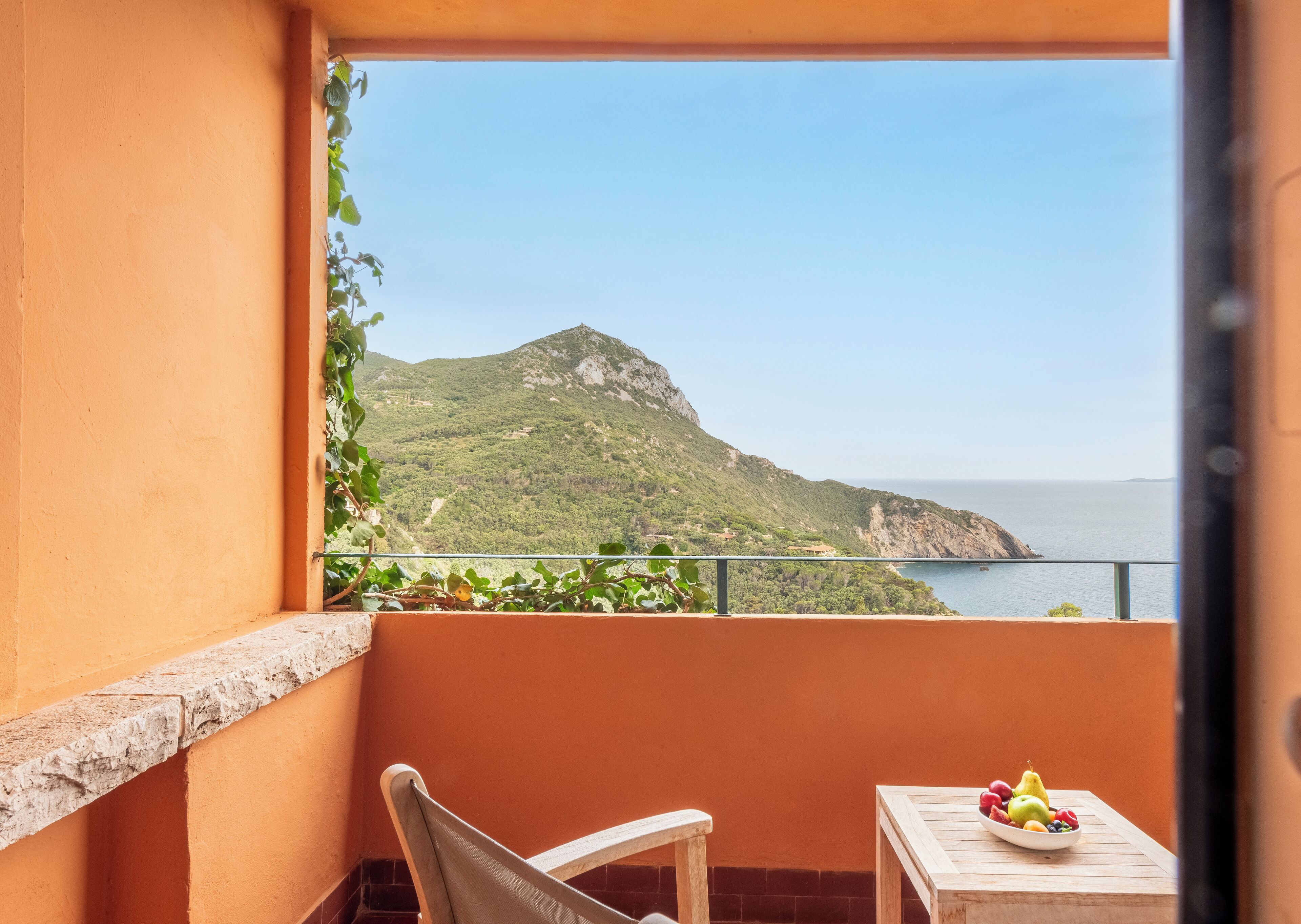 A balcony with a view of a mountainous coastline.