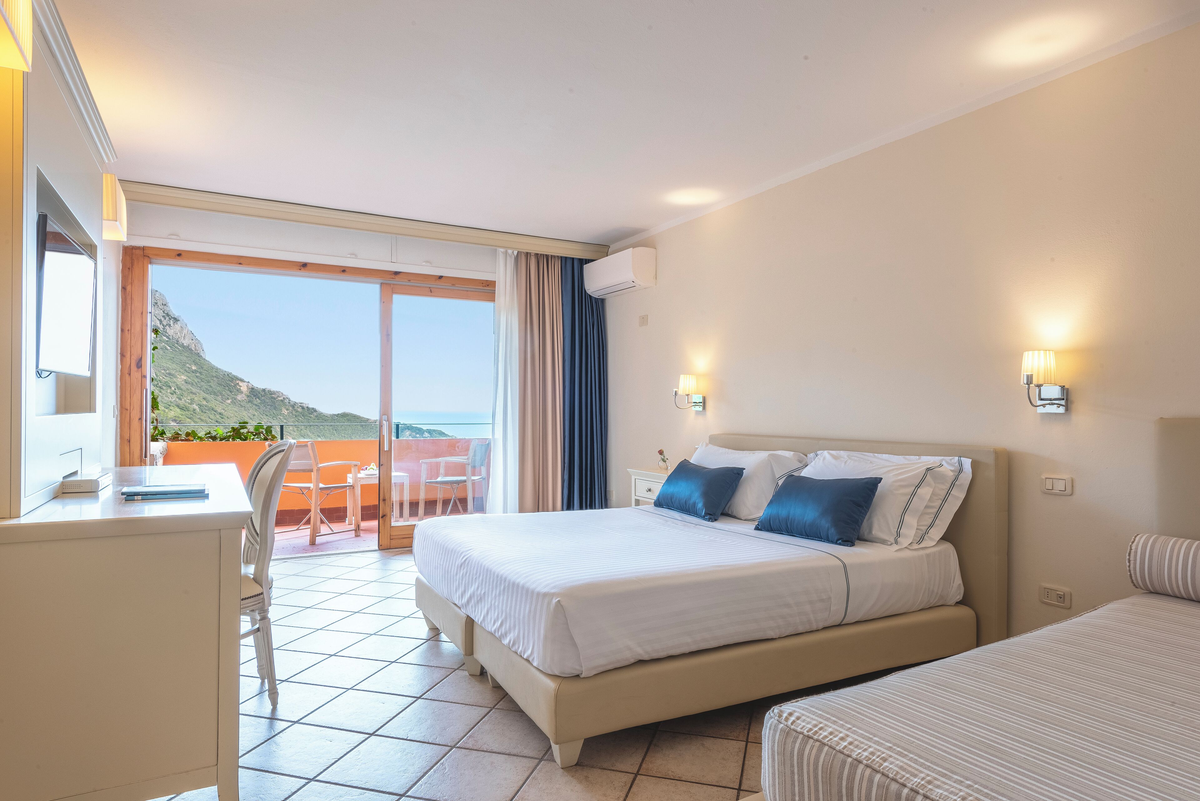 Une chambre d’hôtel avec un lit, un bureau et une vue sur la mer.