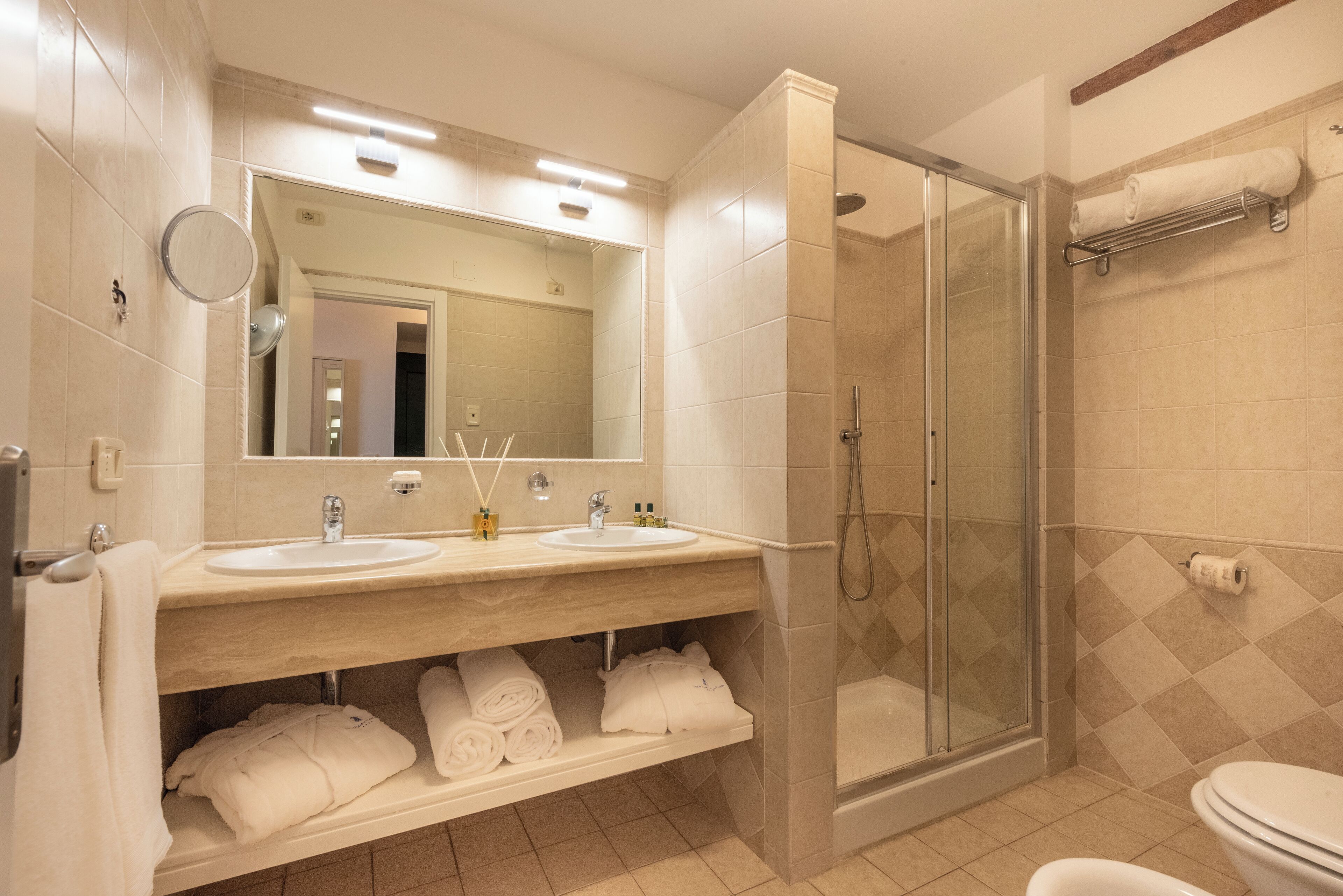 A modern bathroom with two sinks, a glass-enclosed shower, and a toilet.