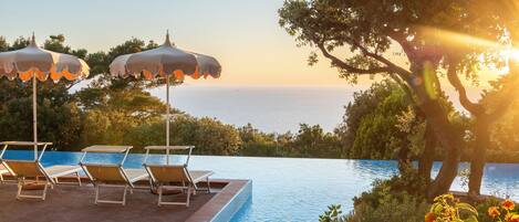 Alberca al aire libre, sombrillas en la alberca y camastros