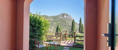 A room with a view of a mountain through an archway, a wooden table, and a chair.