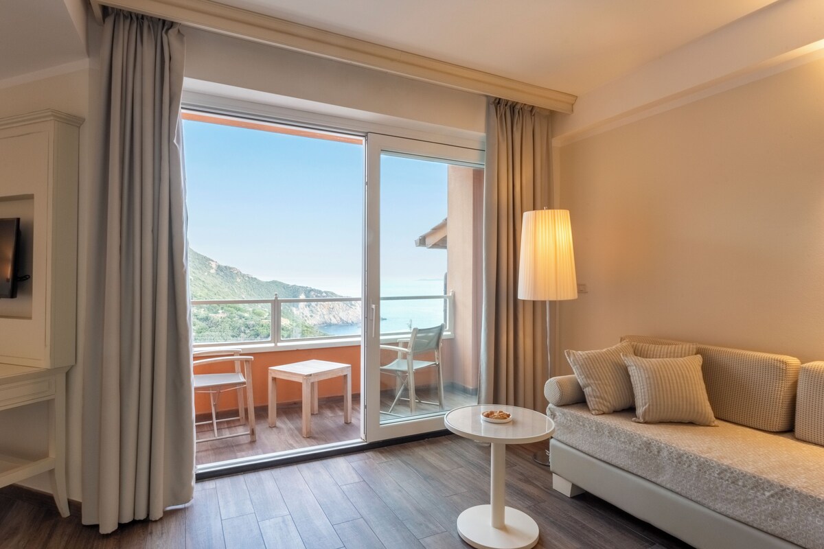 A room with a balcony, a sofa, a table, and a lamp.
