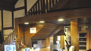 A reception area with a wooden counter, a checkered floor, and a staircase. - Hotel Jägerhof (Langenhagen)