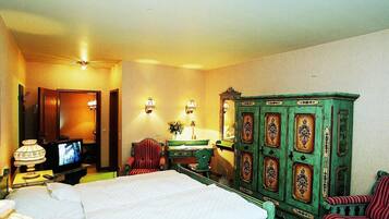 A hotel room with a bed, a television, a desk with a lamp, and a green cabinet.