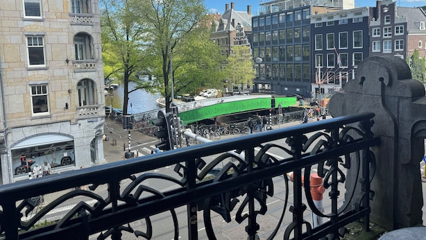 Een uitzicht op een stadsgel met historische gebouwen, een groene brug en een gracht.