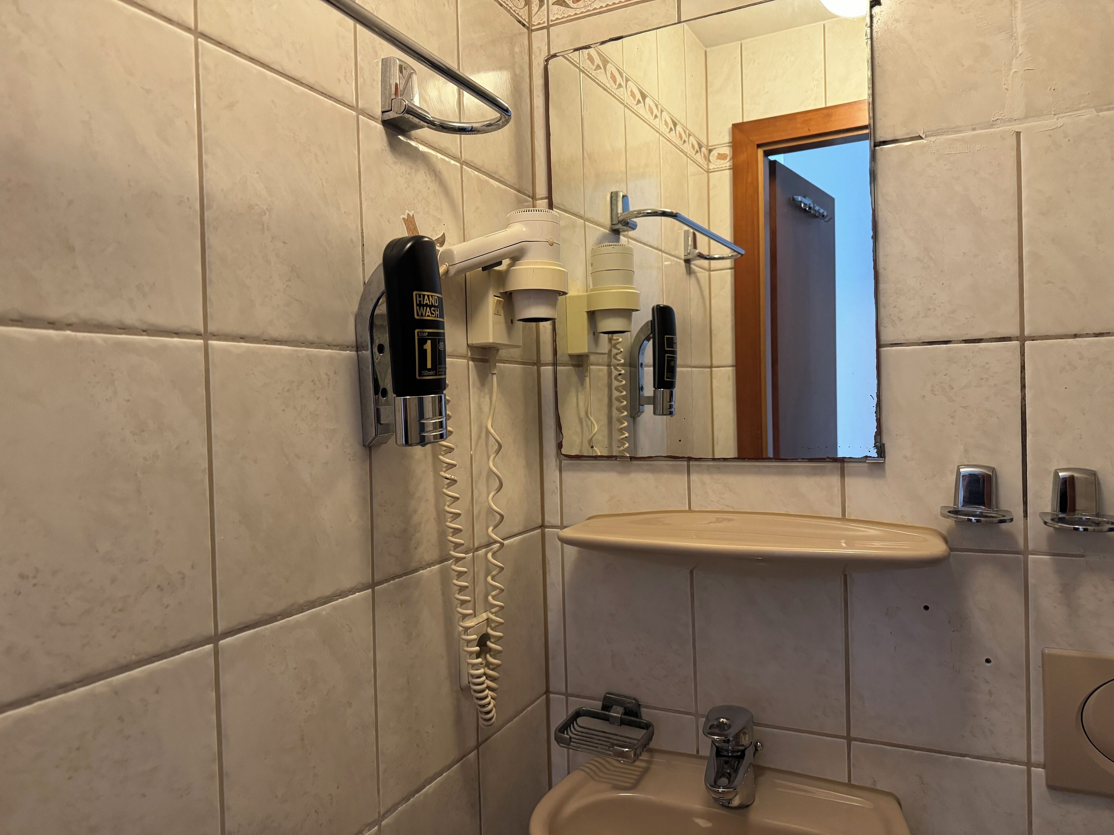 Un baño con zona de lavado de manos, espejo, lavabo y ducha.