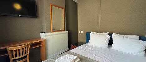 Una habitación de hotel con cama, escritorio, silla, televisión y espejo.