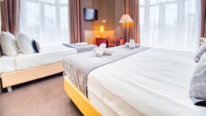 Een hotelkamer met twee bedden, een bureau, een televisie en een lamp.
