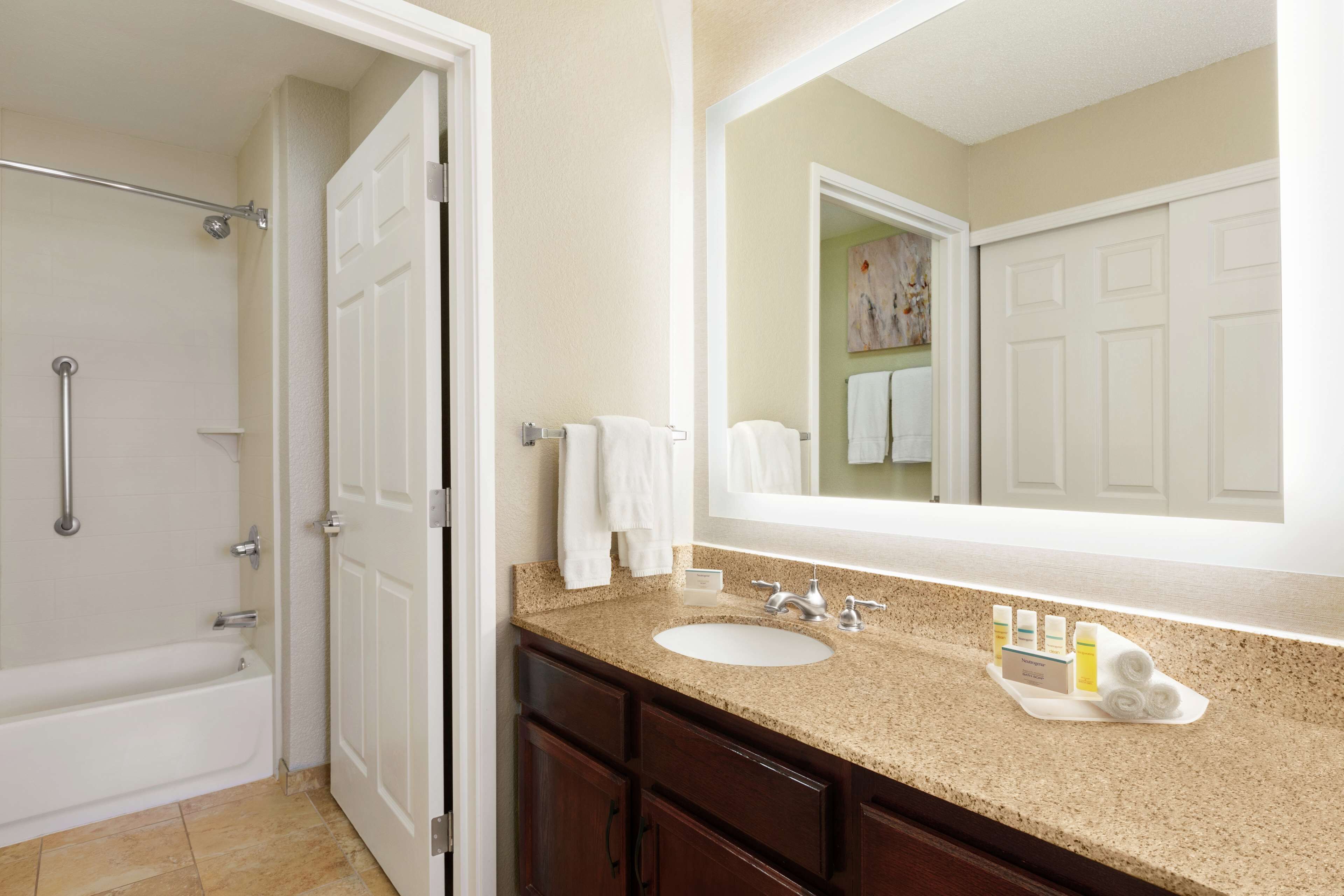A bathroom with a bathtub, a sink, a mirror, and a towel rack.