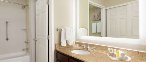 A bathroom with a bathtub, a sink, a mirror, and a towel rack.