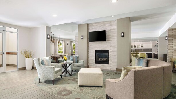 A spacious living area with a fireplace, comfortable seating, and a view of the kitchen.