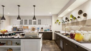 A modern kitchen with white cabinets, a central island, and a breakfast bar.
