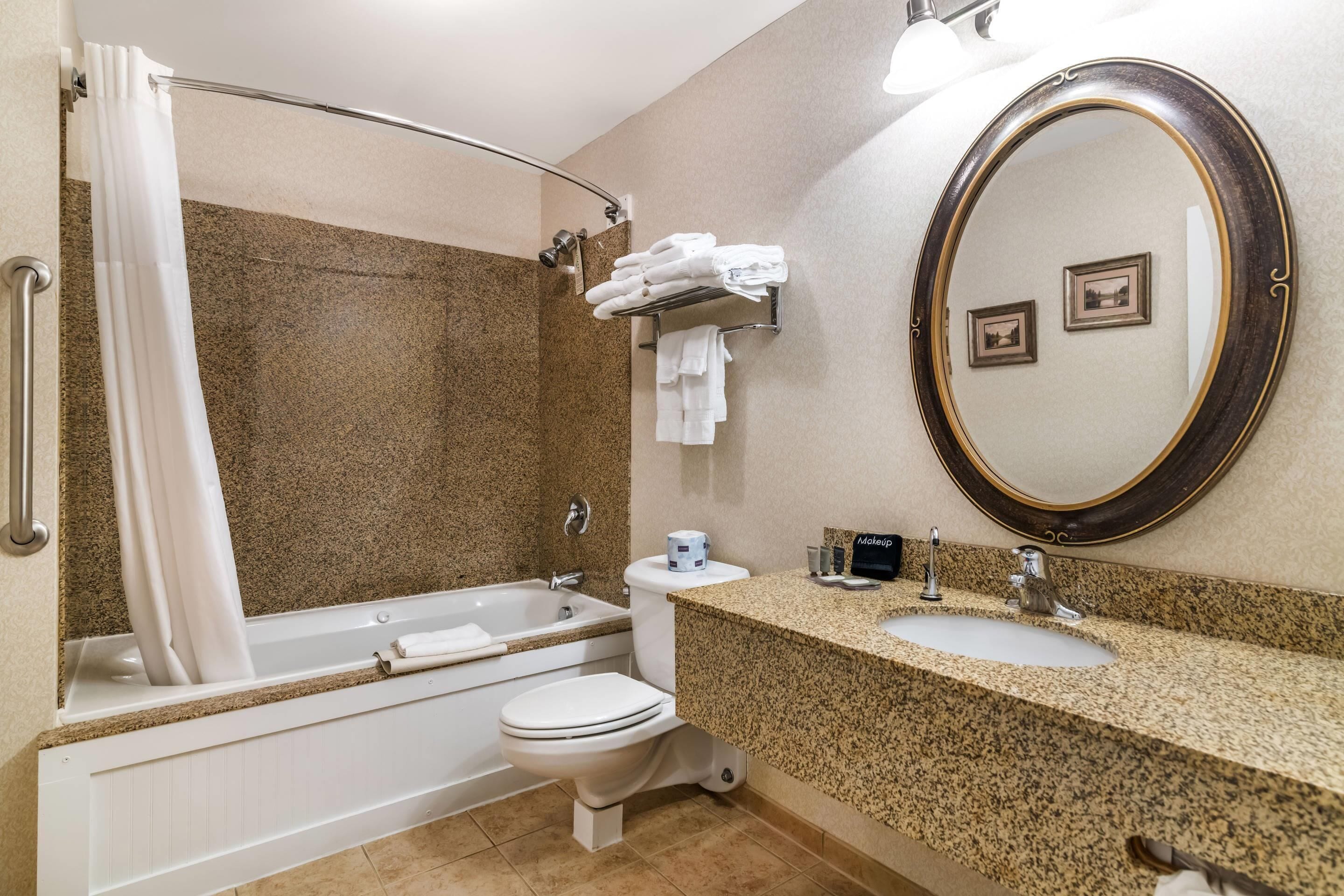 A bathroom with a bathtub, toilet, sink, and a large mirror.