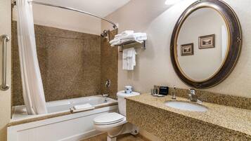 A bathroom with a bathtub, toilet, sink, and a large mirror.