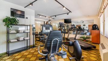 Un gimnasio con varios equipos de ejercicio, una cinta de correr y un espejo grande.