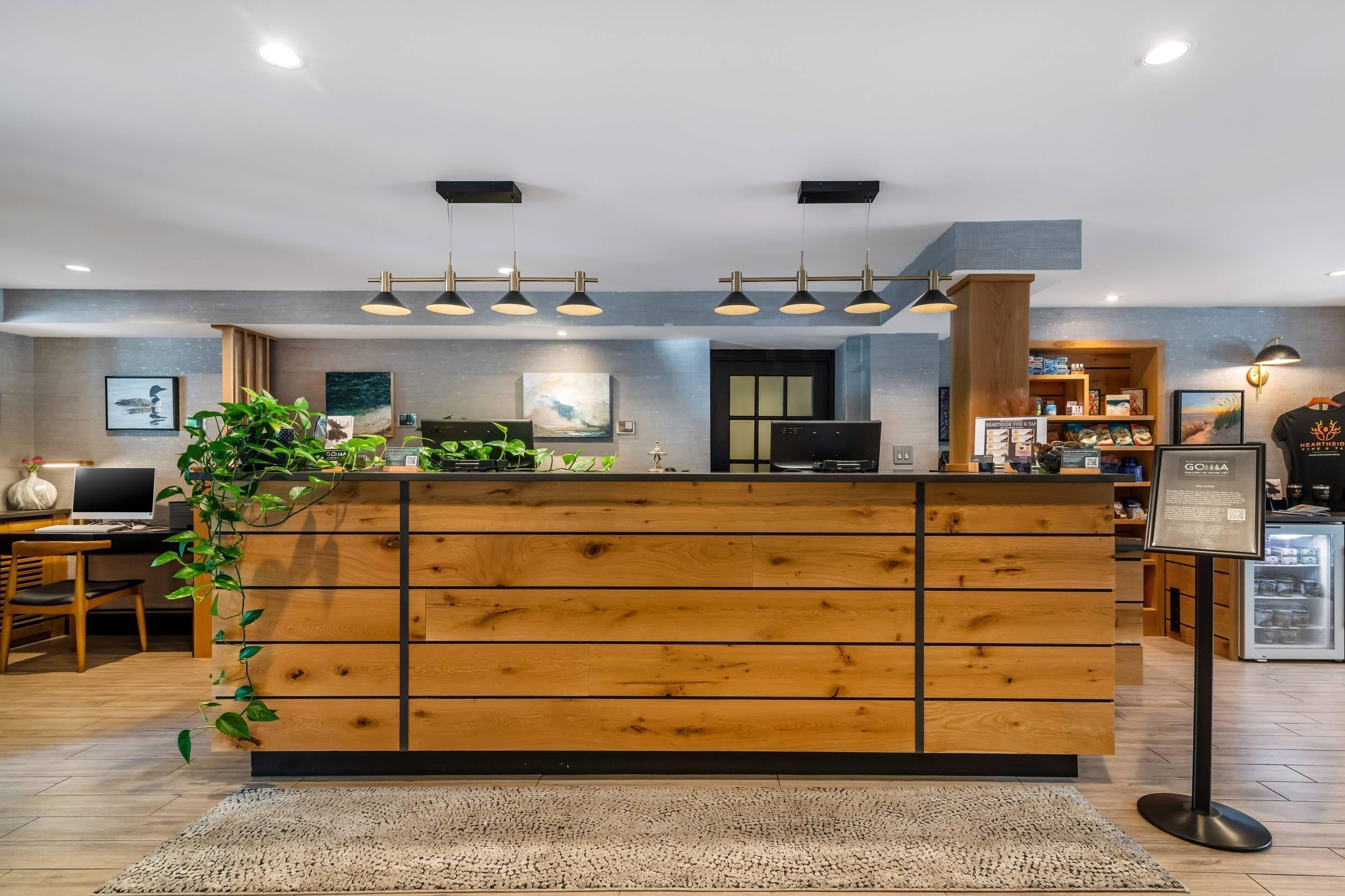A reception desk with wooden panels, a potted plant, and a signboard.
