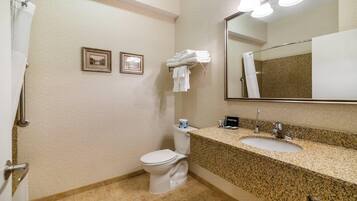 Une salle de bain avec des toilettes, un lavabo et une douche. Deux tableaux encadrés sont accrochés au mur.