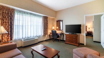 A hotel room with a desk, television, and two patterned sofas.