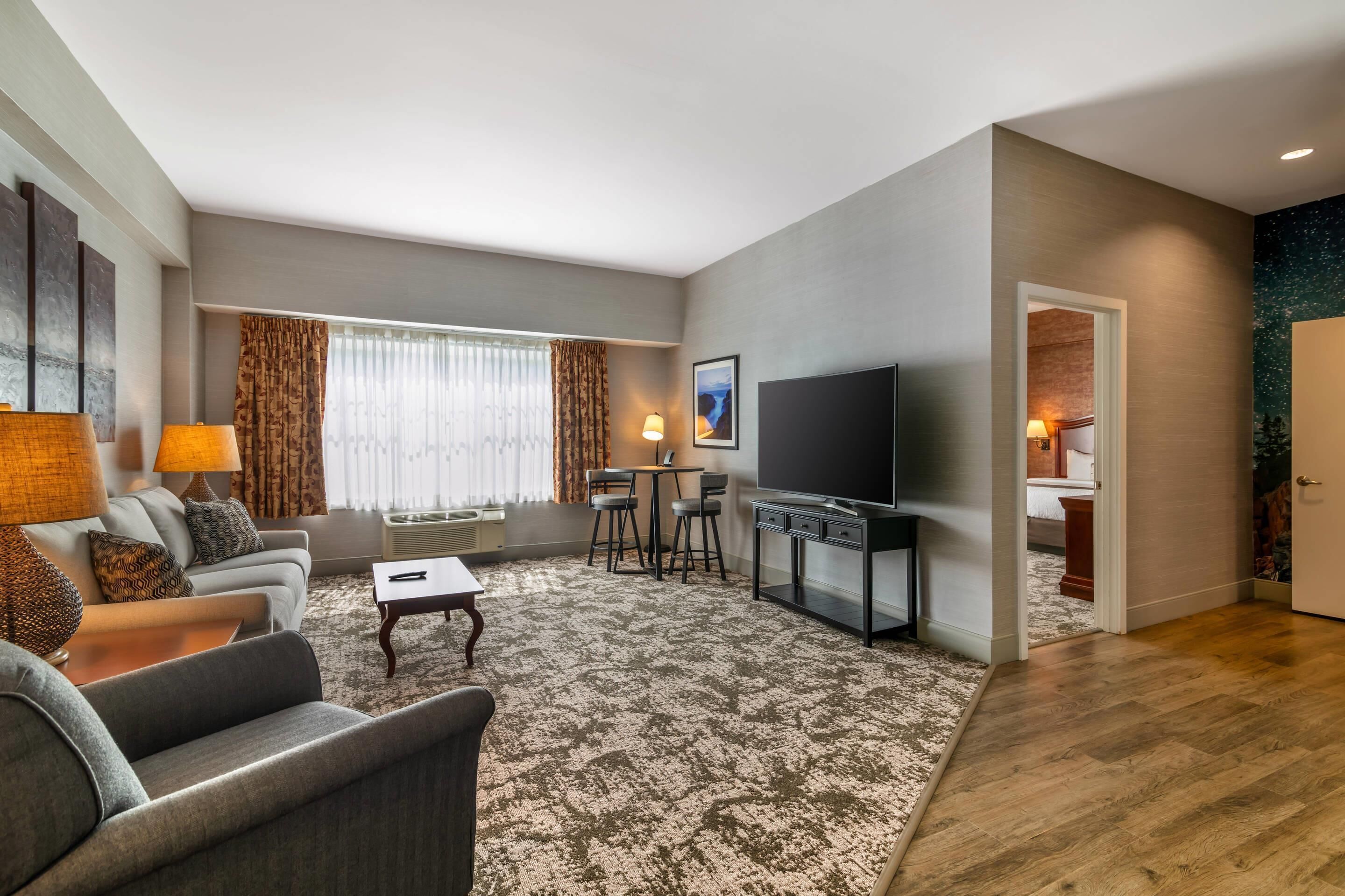Een moderne woonkamer met een bank, salontafel, televisie en een kleine eethoek.