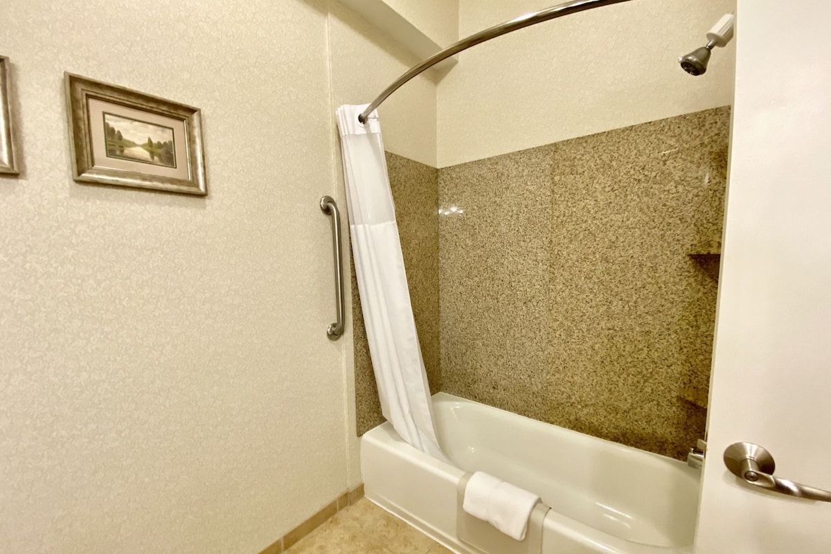 A bathroom with a bathtub, a shower curtain, a towel rack, and a picture on the wall.