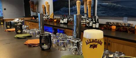A bar area with a large glass of beer, multiple glasses, and a tap system.
