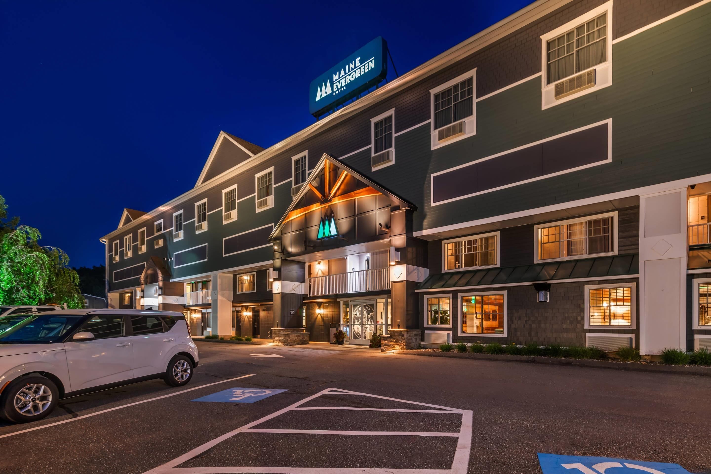 A hotel with a prominent sign reading "MAINE EVERGREEN" and a parking area with marked handicapped spaces.
