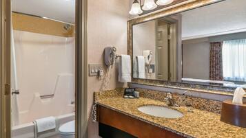 A bathroom with a sink, mirror, and shower.