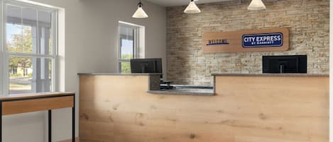 A reception desk with a 'Welcome' sign, a wooden counter, and pendant lighting.