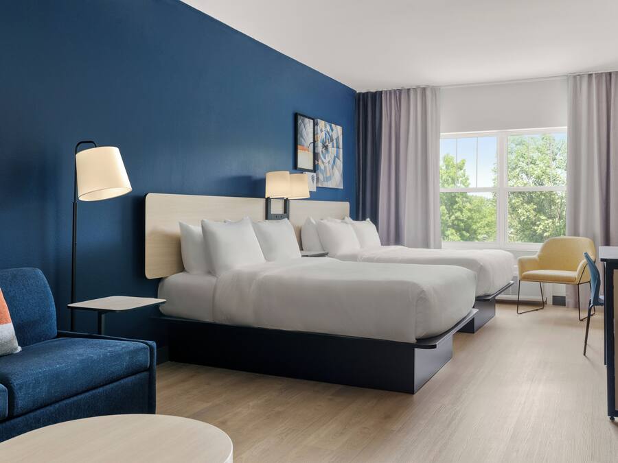 A hotel room with a bed, a desk, a chair, and a couch.
