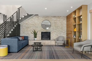 A modern living room with a staircase, a fireplace, and a bookshelf. - City Express By Marriott Gettysburg (Gettysburg)